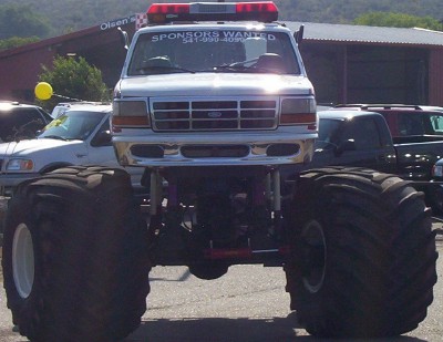 1995 Ford Bronco - Monster truck with oversized tires and a light bar on top, "SPONSORS WANTED" is visible on the windshield.