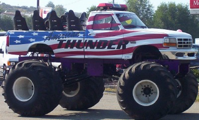 1995 Ford Bronco - This monster truck features patriotic paint and 'AMERICAN THUNDER' lettering on its side.