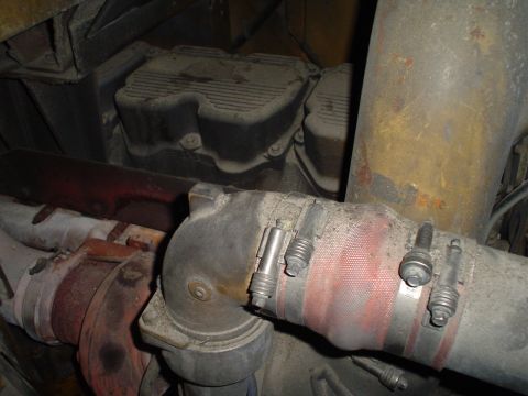 1966 International School Bus - Close-up view of engine components, including hoses and clamps, covered in dust.