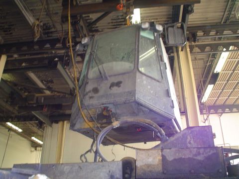 1966 International School Bus - Heavy equipment cab suspended by a crane, likely undergoing maintenance or repair.