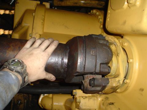 1966 International School Bus - A hand is shown touching a rusty driveshaft connected to yellow machinery.