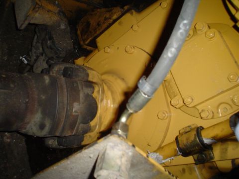 1966 International School Bus - Close-up view of a yellow engine component, showing a hydraulic hose and a driveshaft coupling.