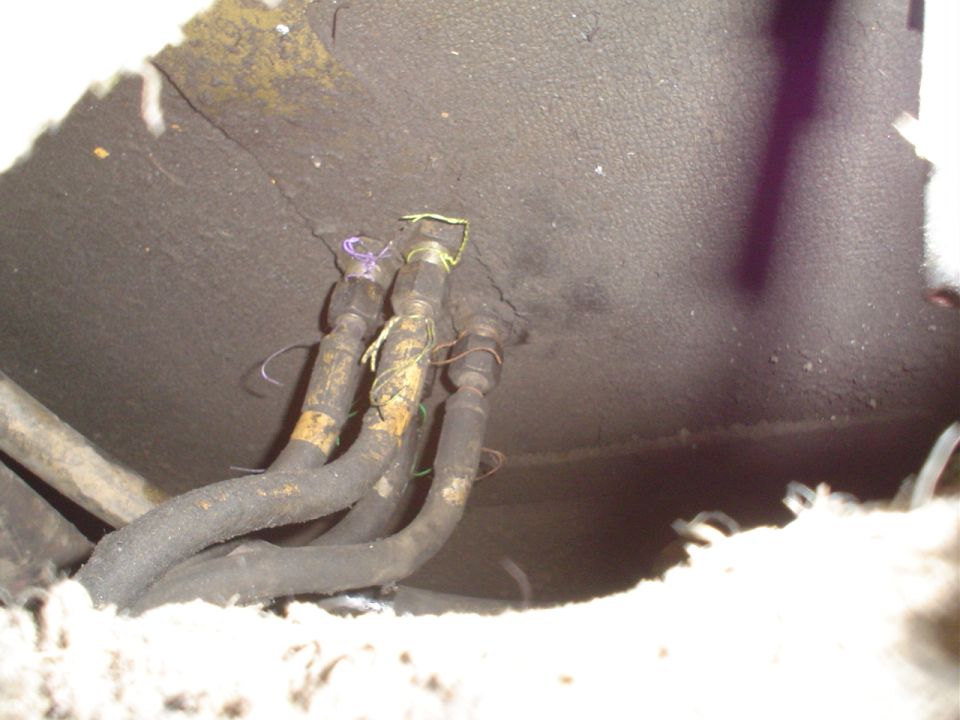 close-up of several black hoses with yellow tape and wires attached, likely fuel lines, under a vehicle