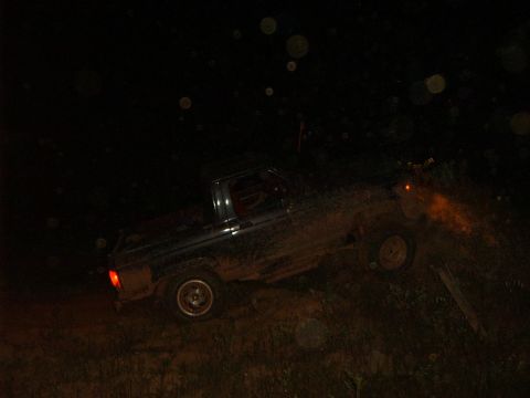 1985 Ford Bronco II - A muddy Ford Bronco II navigates rough terrain in the dark, with its taillights illuminated.