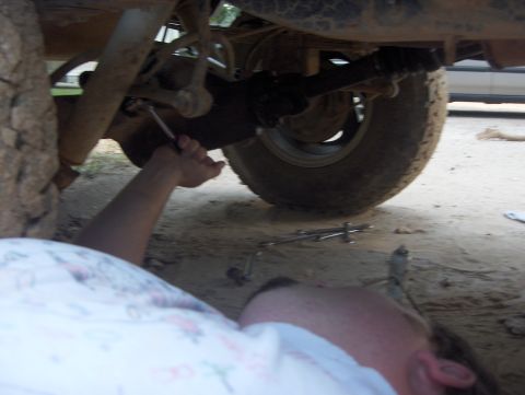 1985 Ford Bronco II - Working on the undercarriage of a vehicle, focusing on the suspension and drive shaft components.