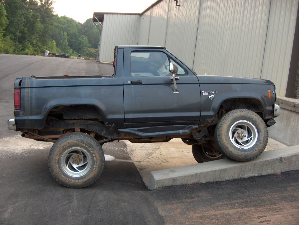 Dark gray 1985 Ford Bronco II parked on a concrete ramp next to a building