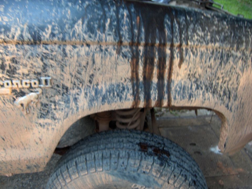 Mud covers the fender and tire of a 1985 Ford Bronco II