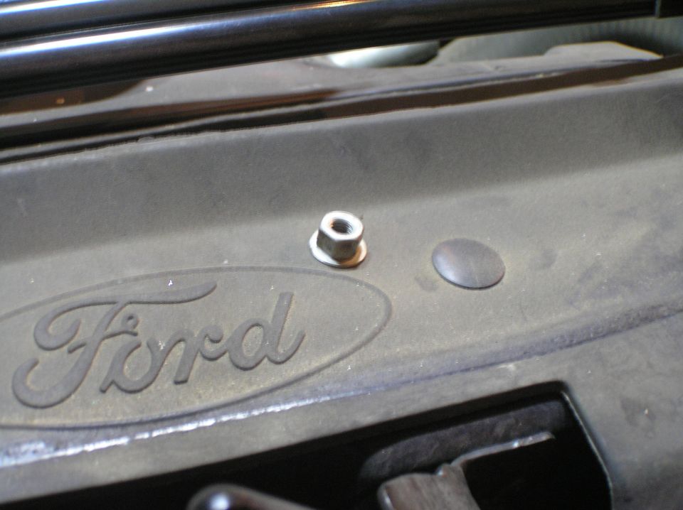 Black Ford-logo engine cover with a flange nut on a stud