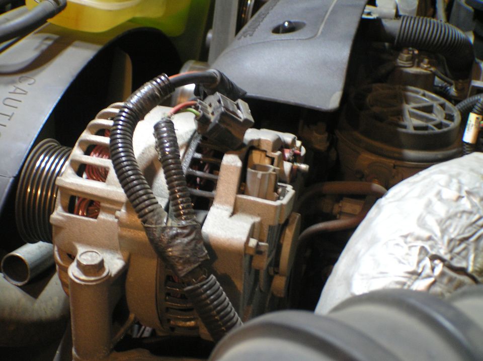 Close-up of an alternator with copper windings and wiring in an engine bay
