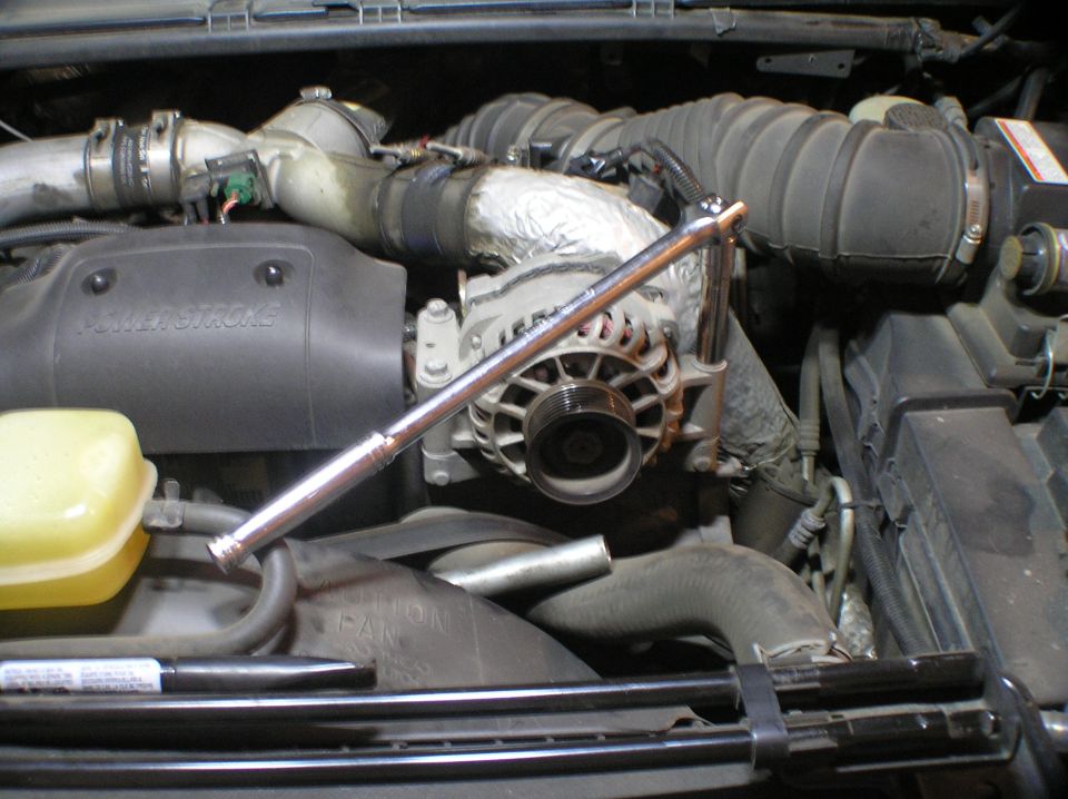 Ford Power Stroke diesel engine bay with breaker bar on alternator and belt tensioner