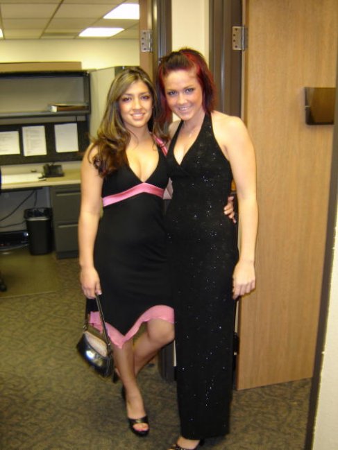 Two women in formal dresses stand in an office hallway