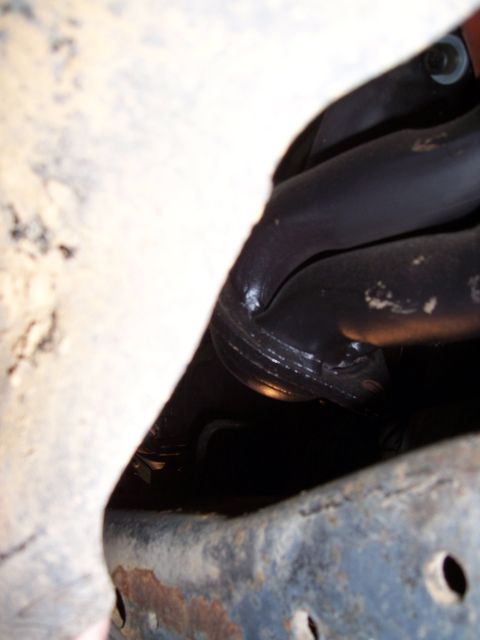 1983 Ford Bronco - A close-up view of a vehicle's exhaust pipe and frame, showing signs of wear and rust.