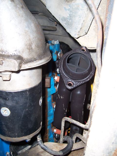 1983 Ford Bronco - Close-up view of engine components, including an exhaust manifold and starter motor.