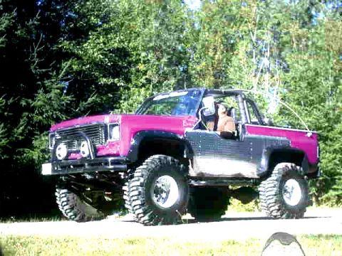 1993 Ford Bronco - This lifted SUV, possibly a GMC Jimmy or Chevrolet K5 Blazer, features a two-tone paint scheme and prominent off-road tires.