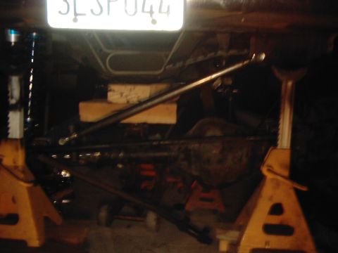 1978 Ford Bronco - The underside of a vehicle is shown, elevated on jack stands for maintenance or repair.