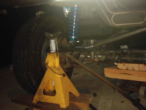 1978 Ford Bronco - The underside of a vehicle is shown, with the rear tire supported by a jack stand and aftermarket shocks installed.
