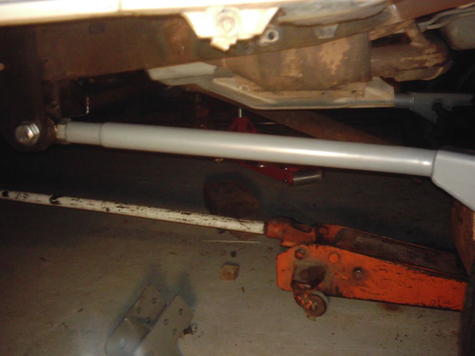 Underbody view of a vehicle with a gray bar and an orange jack
