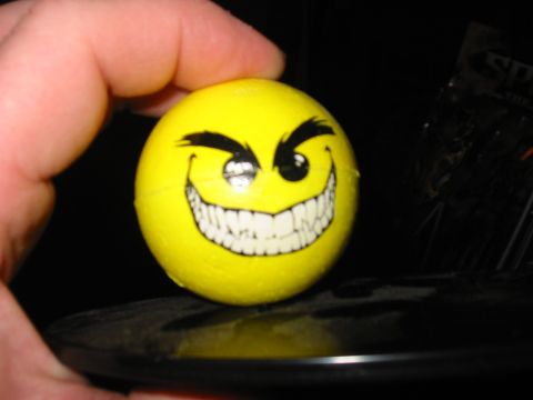 1991 Ford Bronco - A yellow ball with a cartoonish, grinning smiley face is held by a person's fingers.