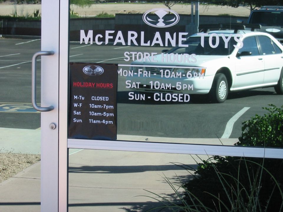 McFarlane Toys store entrance with a white sedan and a dark SUV parked outside