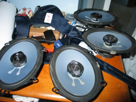 1995 Ford Bronco - A collection of four car speakers are laid out on a table, possibly for installation or repair.