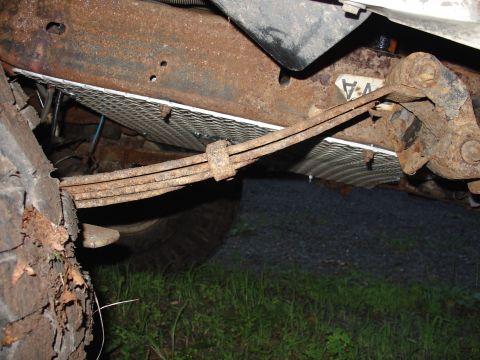 1995 Ford Bronco - The undercarriage of a vehicle shows significant rust on the leaf springs and frame components.