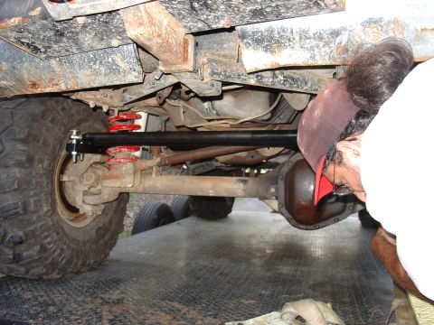 1995 Ford Bronco - Mechanic works on the undercarriage of a vehicle, focusing on the suspension and differential.