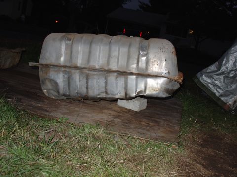 1995 Ford Bronco - A used fuel tank sits outdoors on wooden planks, with a tarp visible to the right.