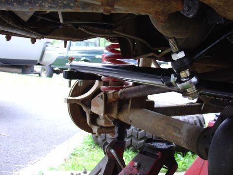 1995 Ford Bronco - Close-up of a vehicle's suspension system, highlighting a new steering stabilizer and other undercarriage parts. Another vehicle is visible…