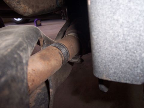 1996 Ford Bronco - Detail of a vehicle's underbody exhaust system, showing a rusted pipe and clamp.