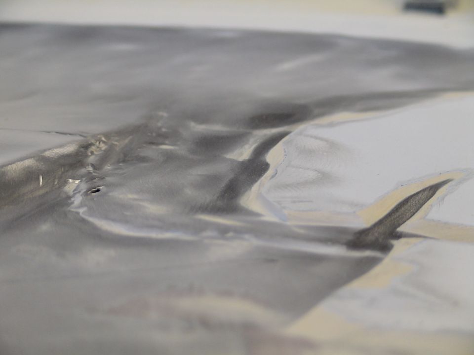Extreme close-up of a polished metallic surface with smudges and reflections