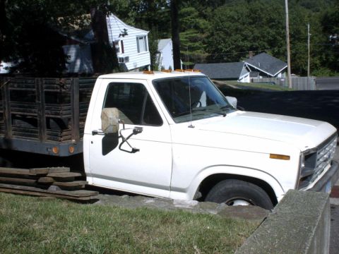 1995 Ford Bronco - This truck appears to be stuck in a ditch, with its front wheel partially submerged in the ground.