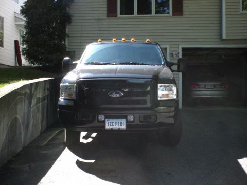 1995 Ford Bronco - A black Ford Super Duty truck is parked in a driveway, with a second vehicle partially visible in the garage.