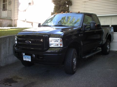 1995 Ford Bronco - This black Ford truck is parked in front of a garage door, with a house visible to the left.