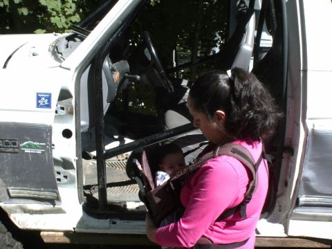 1995 Ford Bronco - A woman holds a baby in a carrier while standing next to the open driver's side door of a white Ford Bronco.