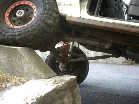 1995 Ford Bronco - This off-road vehicle's front tire is positioned on a rock, revealing its suspension and undercarriage details.