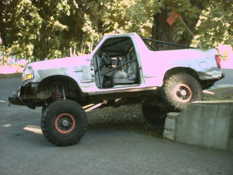 1995 Ford Bronco - Modified 1995 Ford Bronco with lifted suspension and roll cage navigating an obstacle.