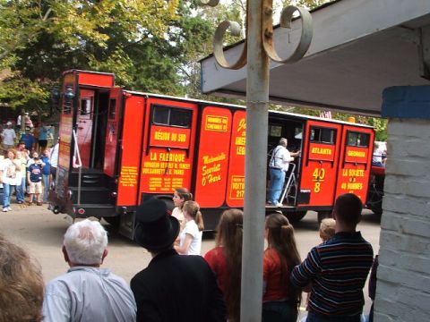 1966 Ford Ranchero - A red train car, possibly a tourist attraction, is shown with people boarding and standing nearby.