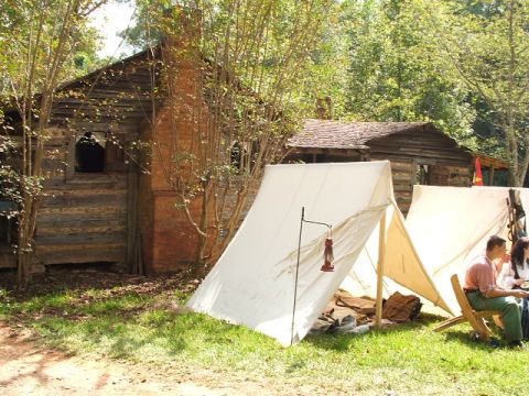 1966 Ford Ranchero - A historical reenactment scene depicts tents and a log cabin with people present.