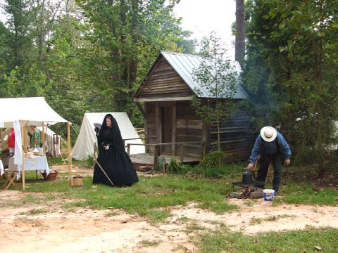 1966 Ford Ranchero - A historical reenactment scene with tents, a small cabin, and people dressed in period attire.