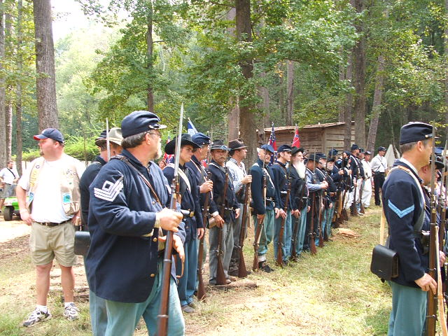 Men in Civil War-era uniforms stand in formation with rifles