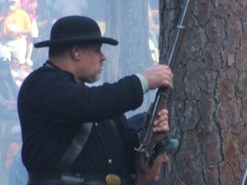 1966 Ford Ranchero - A reenactor in historical attire prepares a rifle during an outdoor event.