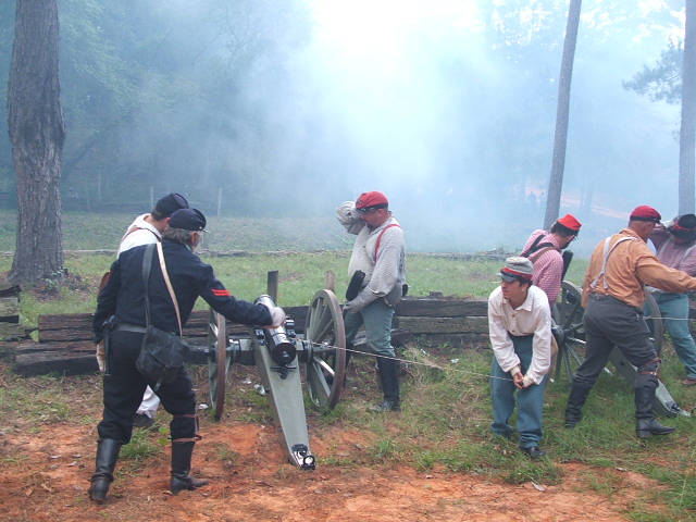 Civil War reenactment scene with men operating a cannon amidst smoke