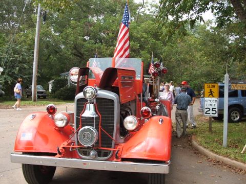 1966 Ford Ranchero - A vintage red fire truck is displayed with American flags, while a blue SUV and a speed limit sign are visible in the background.