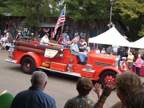 1966 Ford Ranchero - A vintage fire truck participates in a parade, carrying passengers and flying an American flag.