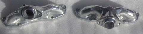 1997 Ford Taurus - Two chrome exhaust manifold parts are displayed on a white surface, likely for automotive aftermarket use.