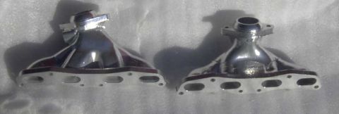 1997 Ford Taurus - Two shiny exhaust manifold parts are displayed side-by-side on a textured white background.