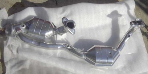 1997 Ford Taurus - This is a chrome exhaust system part, likely a catalytic converter assembly, shown laid out on white material.