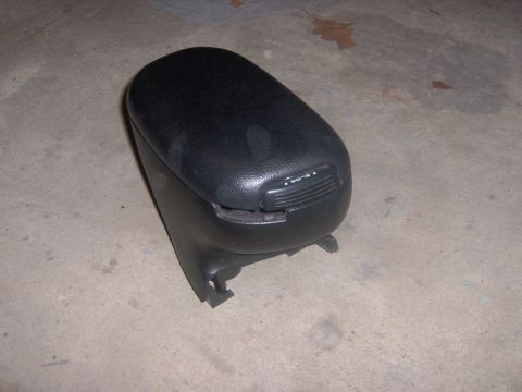 1994 Ford Probe - A black car armrest console with a sliding lid mechanism is shown resting on a concrete surface.
