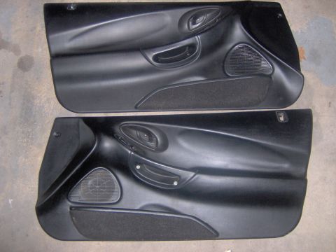 1994 Ford Probe - Pair of black interior door panels, likely for a car, speaker grilles and door handles.
