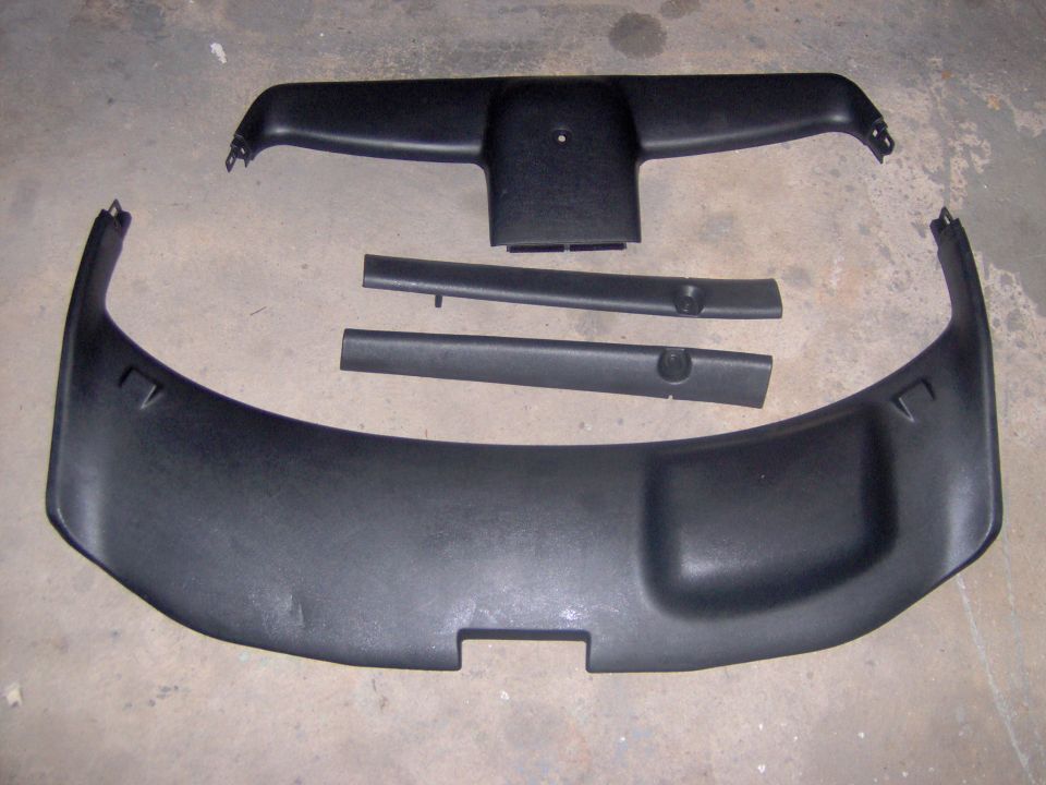 Several black plastic interior trim pieces laid out on a concrete floor